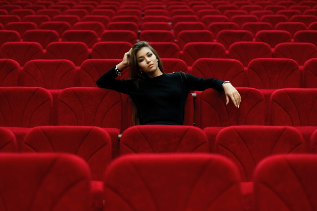 Kvinde sidder alene i teater.